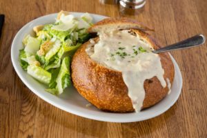 Pier Market’s best clam chowder in San Francisco in a sourdough bowl beside a salad