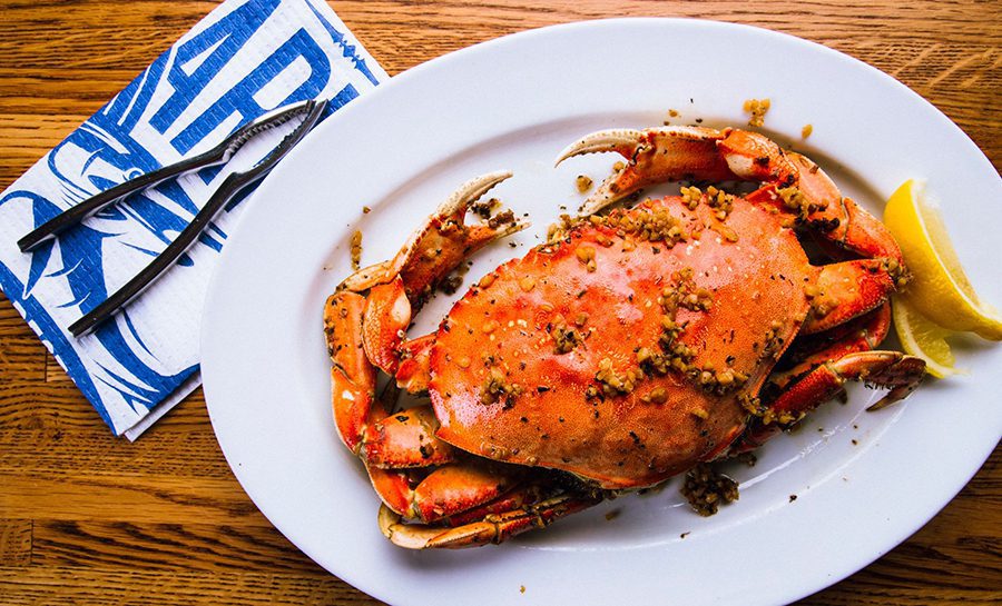 Freshly cooked crab served on a plate with lemon wedges.