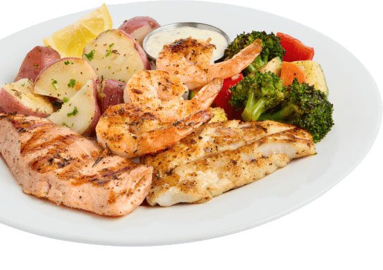 Pier Market Seafood Restaurant Mixed Grill dish with fresh salmon, Pacific cod, shrimp skewer, potatoes, and veg