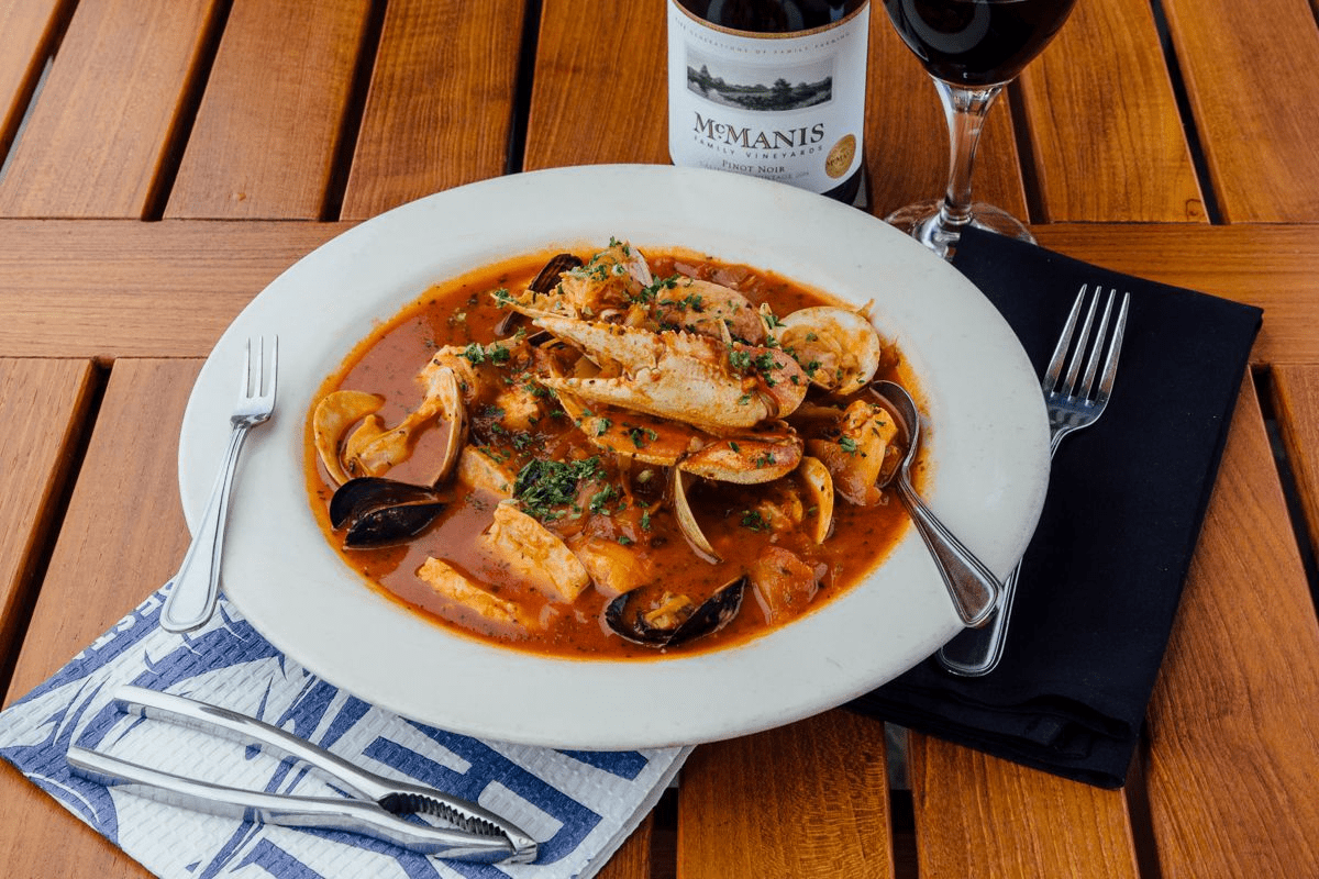 A bowl of cioppino with wine