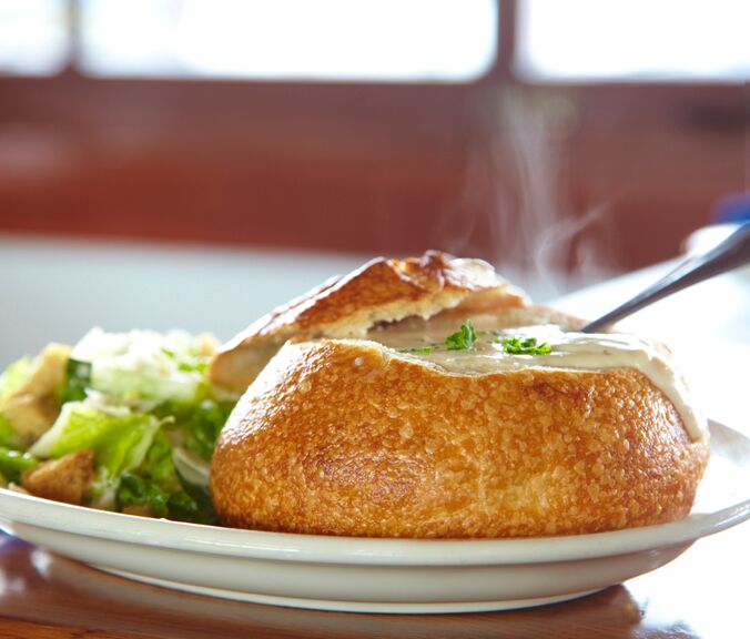 Steaming clam chowder in a sourdough bowl, with salad